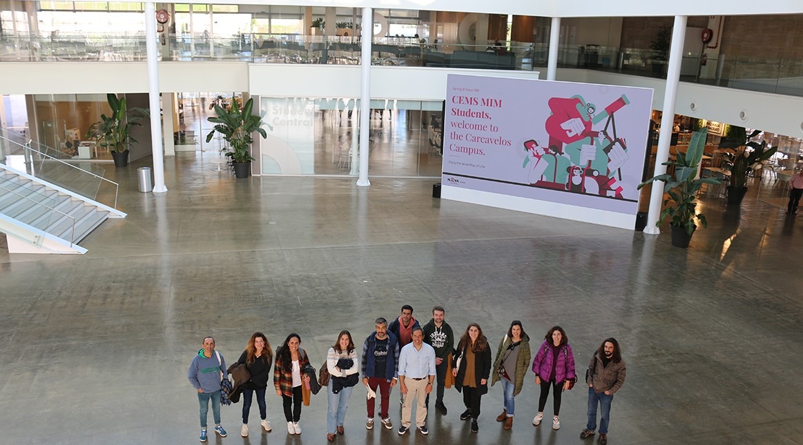 Grupo de profissionais educativos reunidos no hall de um campus universitário